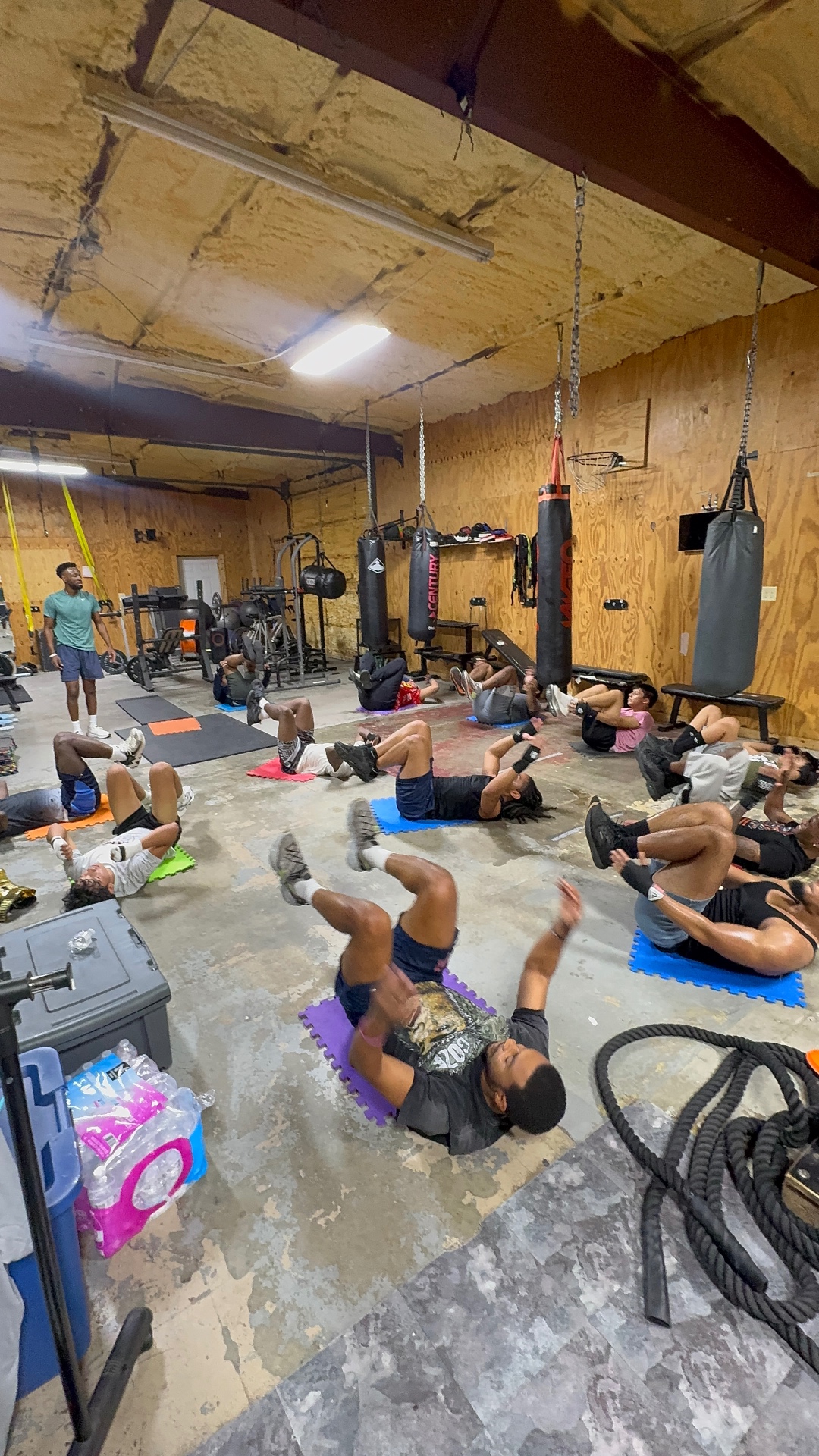 Fit Fighters class doing core and conditioning work on mats in the gym